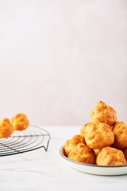 Bir avuç taze kremalı pasta kek beyaz mermer masa kopya alanı ile pembe arka plan üzerinde beyaz bir levha ve tel raf üzerinde. Seçici odak.