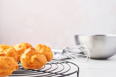 Fırın kavramı. Demet taze kremalı pasta kek üzerinde Fransız tel raf kase, çırpma teli ile kopya alanı ile pembe arka plan üzerinde beyaz mermer masada dishtowel. Seçici odak.