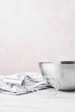 Fırın kavramı. Kopya alanı ile pembe arka plan üzerinde beyaz mermer tablo bulaşık bezi bir çırpma teli ile kase.