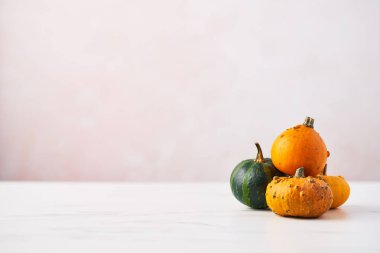 Basit ve modern sonbahar arka plan üzerinde beyaz mermer masa kopya alanı ile pembe arka plan üzerinde sarı, yeşil ve Turuncu kabak ile.