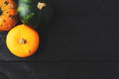 Basit sonbahar arka plan kopya alanı ile siyah ahşap üzerine sarı, turuncu ve yeşil kabak ile. Üstten görünüm.