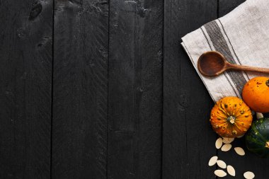 Sonbahar sebze yemek hazırlama. Kopya alanı siyah ahşap zemin üzerine, kabak, kabak çekirdeği, tahta kaşık ve dishtowel üstten görünüm.