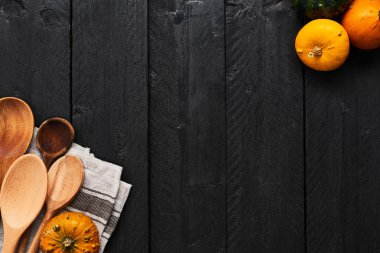 Sonbahar sebze yemek hazırlama. Kopya alanı siyah ahşap zemin üzerine kabaklar, tahta kaşıklar ve dishtowel üstten görünüm.