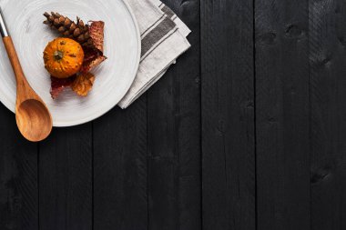 Sonbahar gıda arka plan kavramı. Yuvarlak servis tabağı kopya alanı siyah ahşap tablo üzerinde kabak, süper, yaprakları ve tahta kaşıkla üstten görünüm.