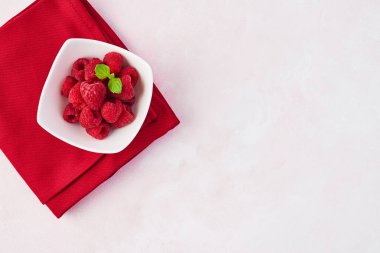 Kopya alanı ile gül arka plan üzerinde beyaz kase taze tatlı ahududu nane ile üstten görünüm bırakır.