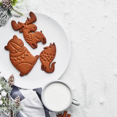 Gingerbread çerezleri sıcak süt içmek ya da yumurta likörü beyaz mermer masada karla kaplı. Ayı, geyik ve fox üstten görünüm şekil gingerbread çerezleri. Kare kırpma.