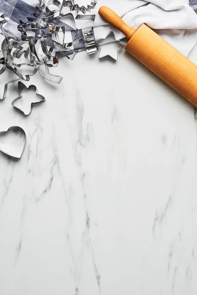 Baking background for baking Christmas cookies with cutters and rolling pin on white marble table. Top view, copy space for text.