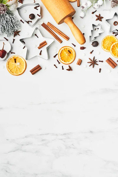 Holiday baking background for baking Christmas cookies with cutters, rolling pin and spices on white marble table with copy space for text. Top view.