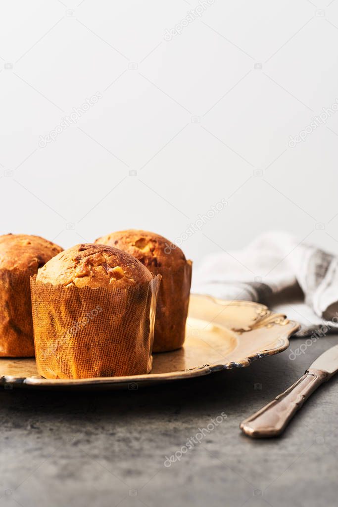 Traditional Christmas mini Panettone with raisins and dried fruits on a old golden serving plate over concrete table. Copy space for text.