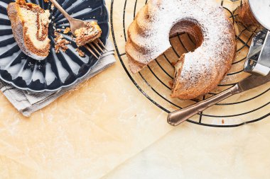 Mermer kek üzerine pudra şekeri ve koyu mavi yan plaka üzerinde pastadan bir dilim ile soğutma rafa kagit üzerinde Fransız. Tatil fırın arka plan. Metin kopyalama yeri olan üstten görünüm.