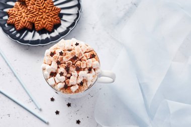 Sıcak çikolata veya kakao ile çırpılmış krema ve hatmi şeker çikolata yıldız ve Noel gingerbread çerezleri üzerinde mavi servis tabağı ile tarçın veya kakao tozu ile serpilir. Üstten görünüm.