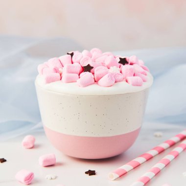 Sıcak çikolata veya kakao şeker kar taneleri ve beyaz mermer masa üzerinde çikolata yıldız Mavi ipek ve pembe bir arka plan üzerinde süslenmiş çırpılmış krem ve pembe krema şeker ile. Kare kırpma.