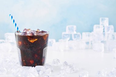 Yaz içeceği buzlu kahve bir bardak mavi arka plan üzerinde beyaz mermer masa buza çevrili saman ile. Seçici odak, kopya alanı metin için. Yatay.