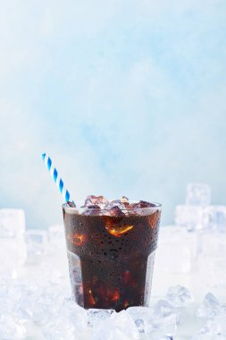 Yaz içeceği buzlu kahve bir bardak mavi arka plan üzerinde beyaz mermer masa buza çevrili saman ile. Seçici odak, kopya alanı metin için.