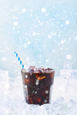 Kış içecek buzlu kahve bir bardak kar ile mavi arka plan üzerinde beyaz mermer masa buza çevrili saman ile. Seçici odak, kopya alanı metin için.