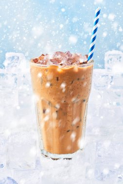 Kış krem buz üstünde kar kar ile mavi arka plan üzerinde çevrili saman ile uzun bir bardak buz kahve iç. Seçici odak, kopya alanı metin için.