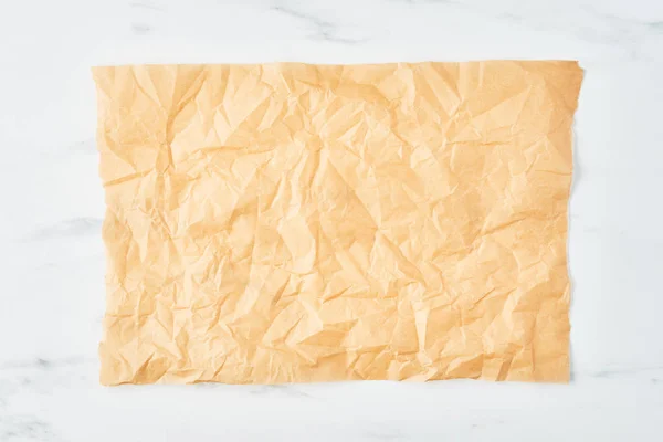 Crumpled Piece Parchment Baking Paper White Marble Table Top View — Stock Photo, Image