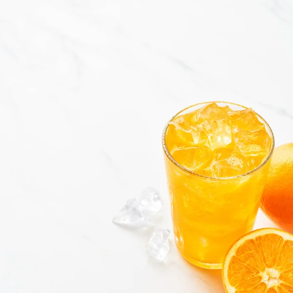 Свежий Апельсиновый Сок Высоком Стакане Апельсином Льдом Белом Мраморном Столе — стоковое фото