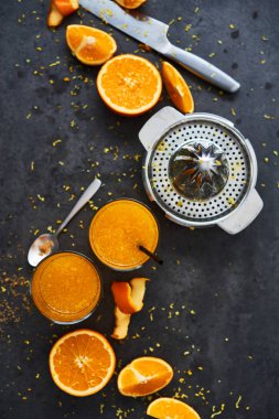 Yaz içeceği. Narenciye sıkacağı ve karanlık beton zemin üzerine portakal dilimleri ile uzun bardak taze portakal suyu. Görünüm sayfa, metin için yer Kopyala. Seçici odak.