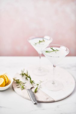 Yaz içeceği. Yaz yenileme biberiye ve narenciye veya köpüklü cin ve beyaz mermer masa pembe bir arka plan üzerinde limonata ile alkollü kokteyl Margarita. Uzay kopyalayın. Seçici odak.