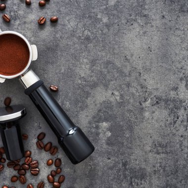 Üstten görünüm kahve arka plan. Çeşitli kahve çekirdekleri, çekilmiş kahve, portafilter ve dış müdahale karanlık beton zemin üzerine. Düz yatıyordu. Metin için yer kopyalayın. Kare ürün. Barista kavramı.