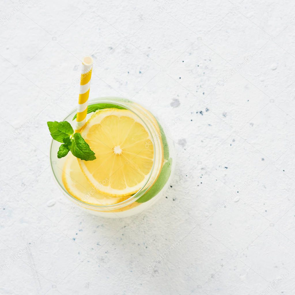 Ice cold summer drink. Traditional lemonade or mojito with lemon, mint and ice on white background. Top view. Copy space for text. Square crop.
