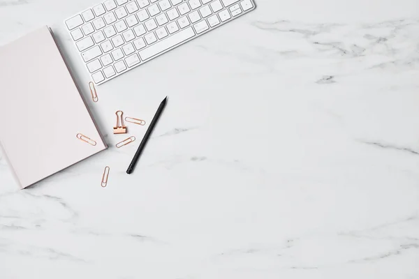 Ofis Masası bilgisayar, pembe günlüğü, pencile ve ataç beyaz mermer zemin üzerinde. Düz yatıyordu. Metin için yer kopyalayın. Üstten Görünüm.