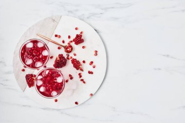 Taze nar suyu buz ve kırmızı nar tohumları üzerinde beyaz mermer plaka mermer arka plan üzerinde hizmet ile. Üstten Görünüm metin için kopya yer ile. Genel gider atış.
