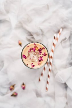 Gül ve kakule kurutulmuş güller ve beyaz ve gri ipek zemin üzerine payet çevrili uzun bir bardak buzlu kahve. Metin kopyalama yeri olan Üstten Görünüm.