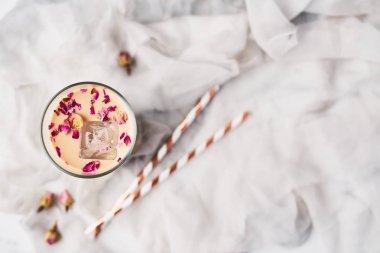 Gül ve kakule kurutulmuş güller ve beyaz ve gri ipek zemin üzerine payet çevrili uzun bir bardak buzlu kahve. Metin kopyalama yeri olan Üstten Görünüm.