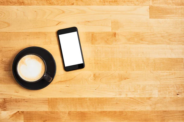 Tazza nera di caffè con smartphone nero su tavolo di legno — Foto Stock