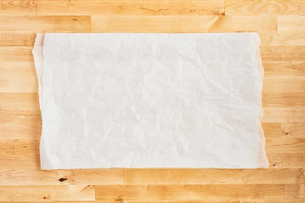 Pedazo arrugado de pergamino blanco o papel de hornear sobre tabla de madera — Foto de Stock