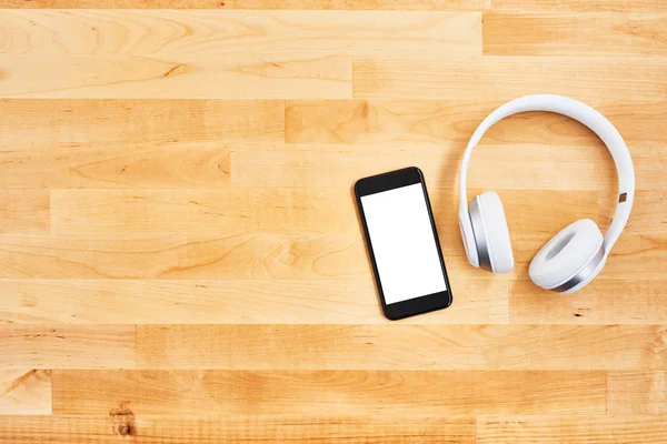 Smartphone and wireless headphone on wooden desk — Stock Photo, Image