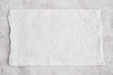 Crumpled piece of white parchment or baking paper on grey concre clipart