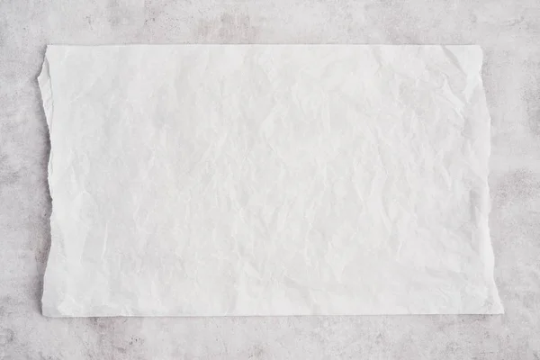 Crumpled piece of white parchment or baking paper on grey concre — Stock Photo, Image