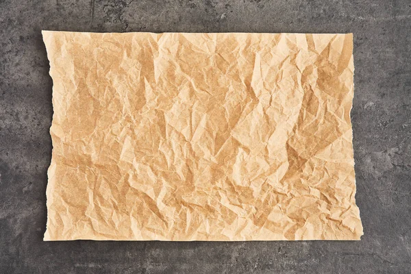 Смятый кусочек коричневого пергамента или бумага для выпечки на черной конкре — стоковое фото