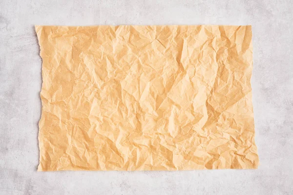 Смятый кусочек коричневого пергамента или бумага для выпечки на серой конкре — стоковое фото
