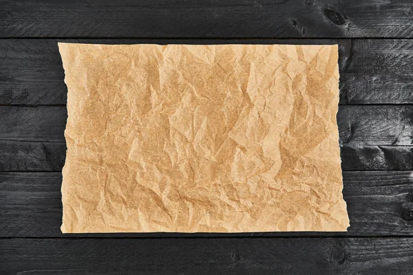 Pièce froissée de papier sulfurisé ou de papier sulfurisé sur table en bois noir — Photo