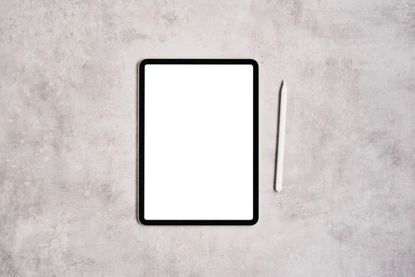 Gri beton arka plan üzerine tablet ve kalem.