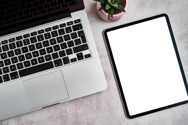 Gri beton arka planda açık dizüstü bilgisayara sahip dijital tablet.