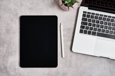 Gri konkret üzerinde dijital tablet ve beyaz kalem ile açık dizüstü bilgisayar