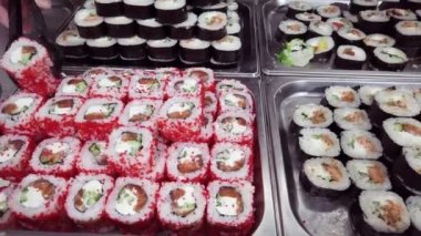Geleneksel suşi tepsilerde servis marketi 4K 'de sıra sıra yuvarlanıyor. İnsanlar tepsiden farklı suşi çeşitleri seçiyor. Bir sürü renkli suşi seçimi..