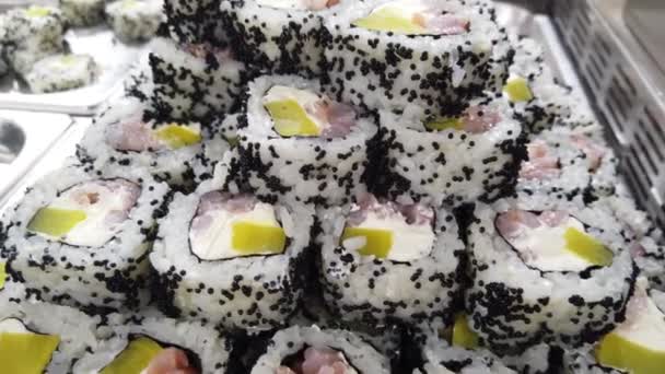 盘中的日本寿司卷排成一排 在展台市场上销售 寿司卷与鳄梨 奶酪和鲑鱼4K镜头 — 图库视频影像