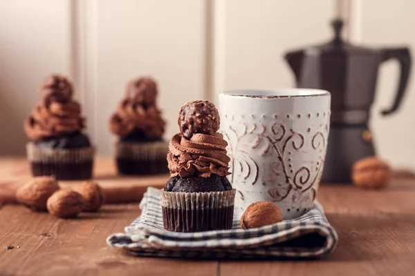 Tasty chocolate cupcakes on wooden board. Cup of coffee. Geyser coffee maker.