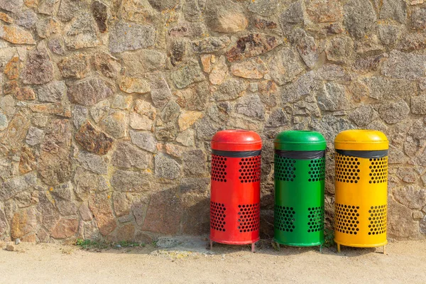 Three multicolored recycle bins for waste near the wall. Sort waste