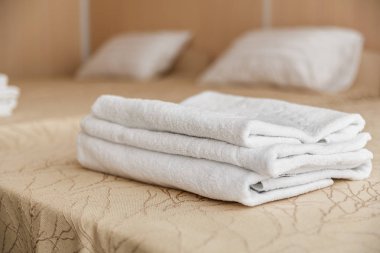 Yatakta otelde beyaz otel havlu yığını. Yumuşak odak.