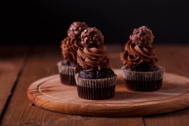 Ahşap tahta üzerinde lezzetli çikolata cupcakes. Koyu arka plan
