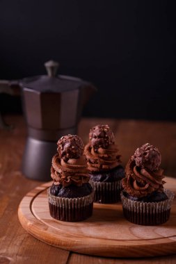 Ahşap tahta üzerinde lezzetli çikolata cupcakes. Koyu arka plan