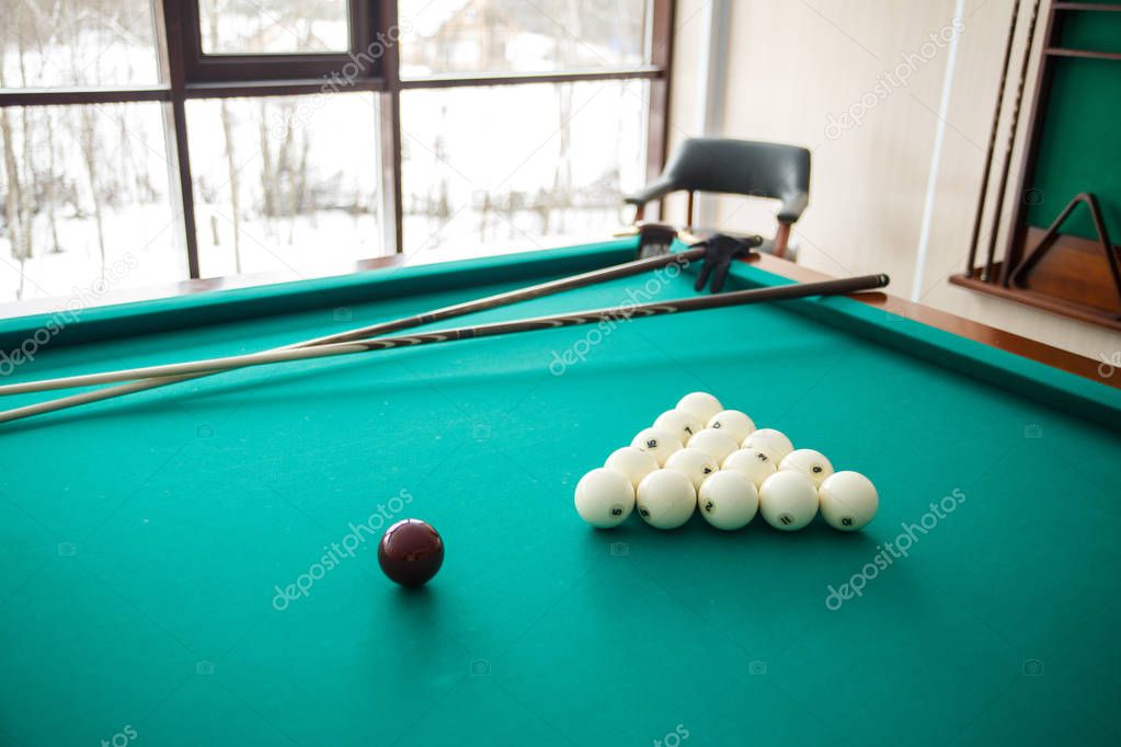 Cue ball for Russian billiards on the table. White billiard balls on the background. Green cloth. Selective focus.
