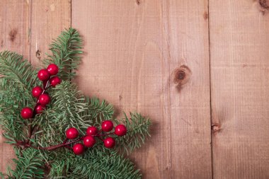 Noel köknar ağacı ahşap arka plan üzerinde. Kırmızı meyveler. Rustik tarzı. Üstten görünüm. Kopya alanı.